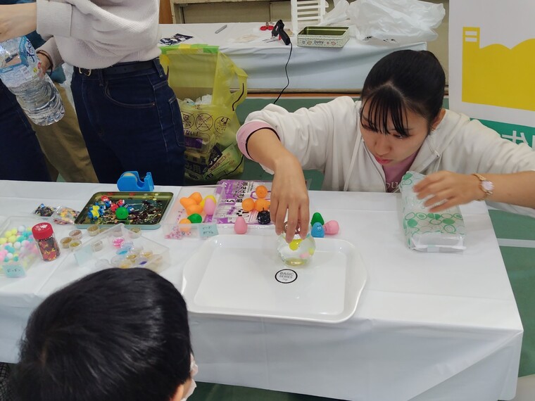 子どもにスノードームの作り方をレクチャーする学生