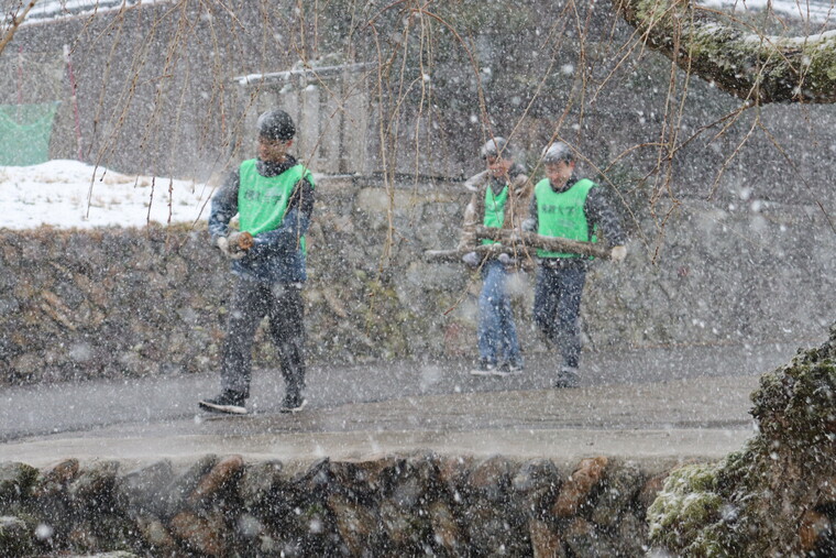 雪の中、椎茸の菌打ちを行う原木を運搬